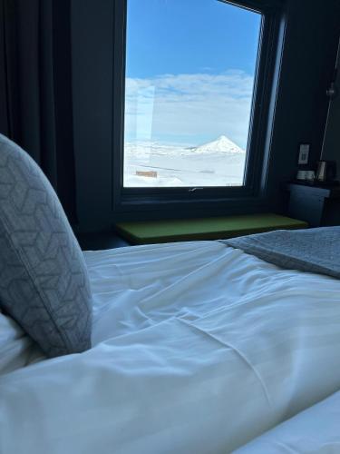 a white bed in a room with a large window at Hótel Laxá in Myvatn