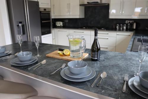 eine Küche mit einem Tisch mit einer Flasche Wein und Gläsern in der Unterkunft Four Corners Holiday Home Hot Tub & Sauna in Ferndown