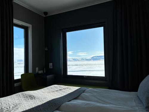 a bedroom with a bed and two large windows at Hótel Laxá in Myvatn