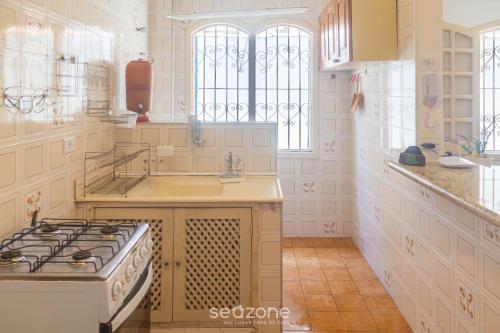 a white kitchen with a stove and a sink at Elegante Apto a 3 minutos da Praia Grande BTI003 in Ubatuba