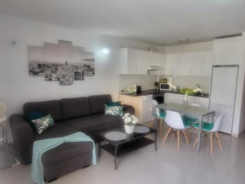 sala de estar con sofá, mesa y cocina en Apartamento Sol & Arena, en Puerto de Santiago