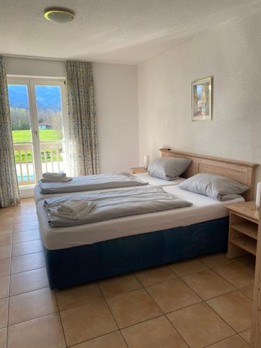 1 dormitorio con 2 camas y ventana grande en Appartementresidenz König Ludwig en Übersee