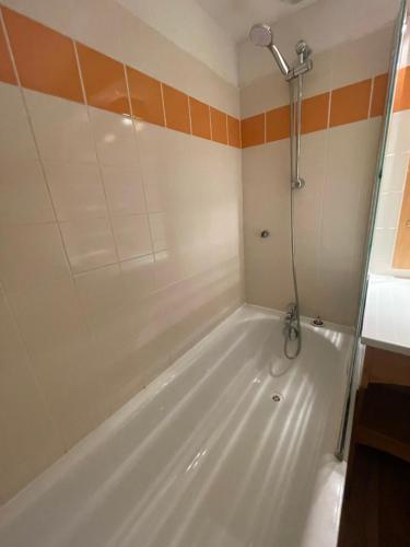a bath tub with a shower in a bathroom at Droseras A02 - Chamrousse 1700 - Les Villages du Bachat in Chamrousse