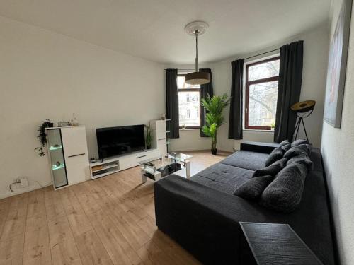 ein Wohnzimmer mit einem schwarzen Sofa und einem Flachbild-TV in der Unterkunft Ferienwohnung In Bremerhaven in Bremerhaven