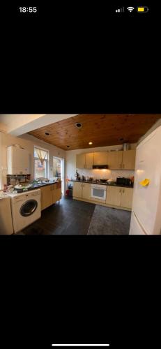 a large kitchen with white cabinets and a white refrigerator at Best room- Near London luton Airport and close to Restaurants shops and Dunstable hospital in Luton