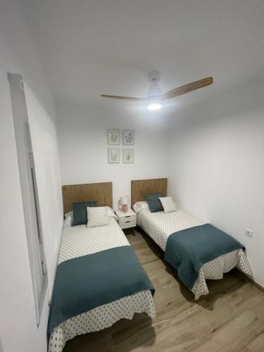 Apartamento Vitelio في كارمونا: سريرين في غرفة بجدران بيضاء
