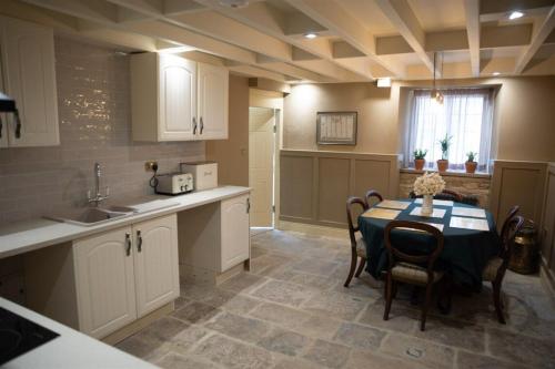 a kitchen with a table and chairs and a kitchen with white cabinets at The Grooms Cottage in Longwitton