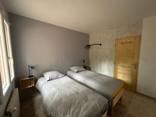 two twin beds in a room with a door at Maison au Pied de la Sainte Victoire in Puyloubier