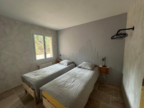 two twin beds in a room with a window at Maison au Pied de la Sainte Victoire in Puyloubier