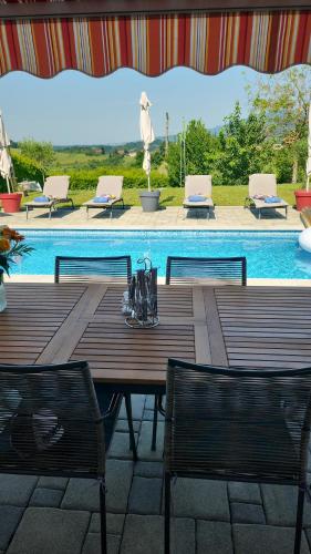 einen Holztisch und Stühle neben einem Pool in der Unterkunft Villa 3 chambres piscine Croatie in Donje Makojišće