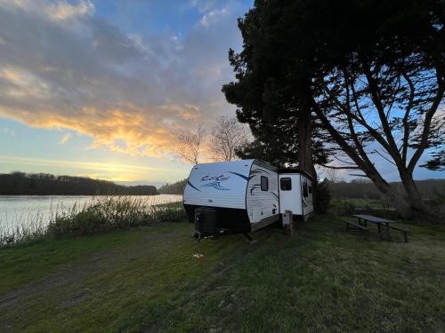 a trailer parked in a field next to a lake at Surfside Glamping camper in Klamath