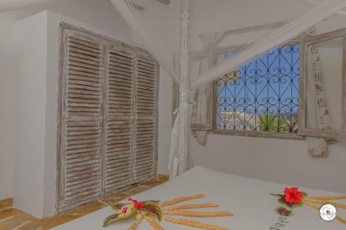 um quarto com uma cama com uma janela e flores vermelhas em Kenya Residence Watamu em Watamu