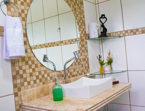 a bathroom with a sink and a mirror at Pousada Encantos do Glória in São João Batista do Glória