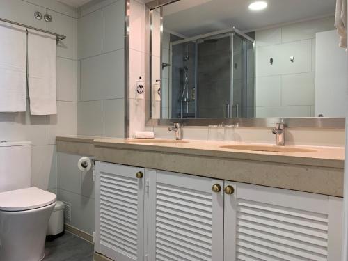 a bathroom with two sinks and a toilet and a mirror at Discovery Apartment Carnaxide in Carnaxide