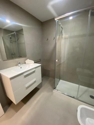 uma casa de banho com uma cabina de duche em vidro e um lavatório. em Estudio Deluxe Hercules em Sevilha