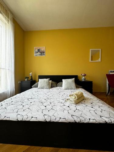 a bedroom with a large bed with a yellow wall at Extralarge Queen Room in the Heart of Bratislava with Terrace in Bratislava