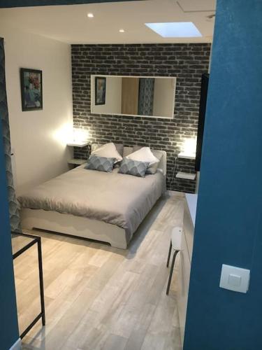 een slaapkamer met een bed en een bakstenen muur bij Suite atypique de qualité in Orsay