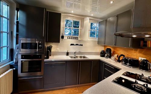 - une cuisine avec des placards noirs et un évier dans l'établissement Maison de famille La Baule les pins, à La Baule