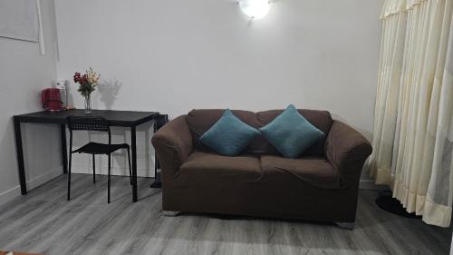 a brown couch with two blue pillows in a living room at Bright and Cozy Room with Free Parking in Edmonton