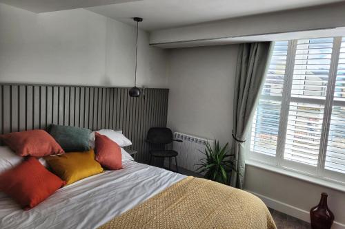 a bedroom with a bed with colorful pillows and a window at Sgwâr in Menai Bridge