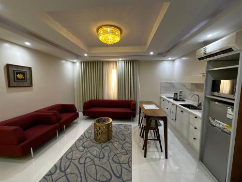 a living room with red couches and a kitchen at Lovely High Quality Self Check-in Apartments شقق سلام بالدخول الذاتي in Medina
