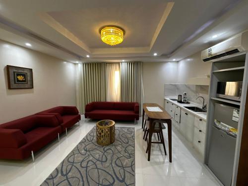 a living room with red couches and a kitchen at Lovely High Quality Self Check-in Apartments شقق سلام بالدخول الذاتي in Al Madinah