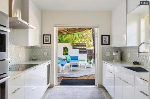 cocina con armarios blancos y sala de estar. en New Hidden Oasis by Brightwild- Waterfall Pool Close to Beach, en Key West