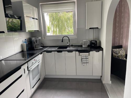 een witte keuken met een wastafel en een raam bij Promienna Rezydencja - bright holiday home in Wolin