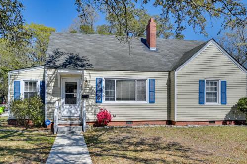 a white house with blue shutters and a chair at New Bern House with Gas Grill Near Neuse River! in New Bern