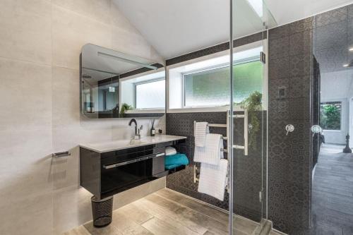a bathroom with a sink and a glass shower at Artistic Mount Vic Villa in Auckland