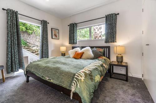 a bedroom with a bed and two windows at Artistic Mount Vic Villa in Auckland