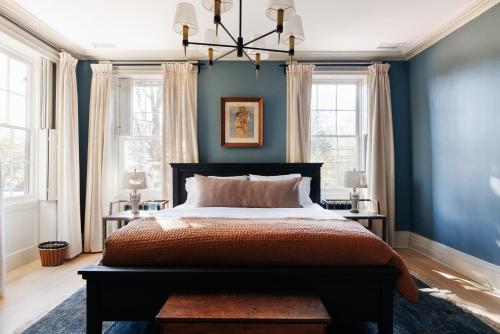 een slaapkamer met een bed met blauwe muren en ramen bij Serene Estate - Heated Saltwater Pool, Sauna, 5 Mins to Hudson in Catskill