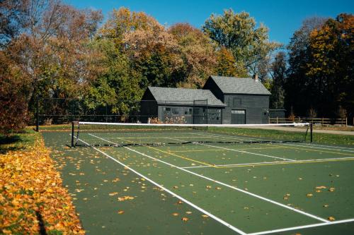 een tennisbaan met een gebouw op de achtergrond bij Serene Estate - Heated Saltwater Pool, Sauna, 5 Mins to Hudson in Catskill