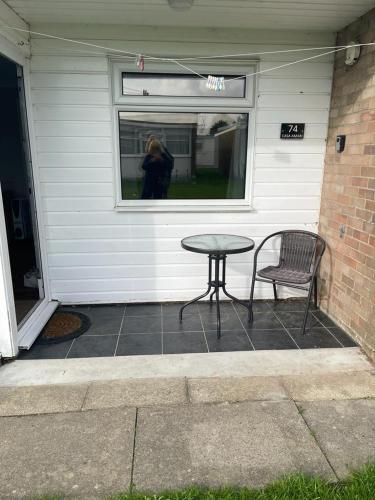 a table and a chair in front of a house at Seabreeze Number 74 includes swimming passes and club entry in Scratby