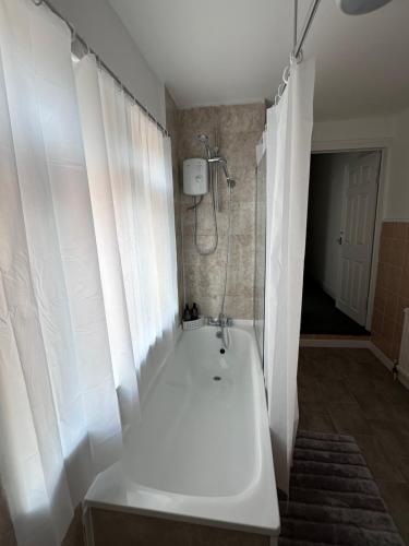 a bathroom with a shower and a white bath tub at 3 bed house in Leicester! in Leicester