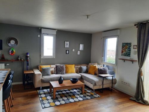 a living room with a couch and a table at Magnifique appartement avec terrasse et parking, 8 Personnes in Nanterre