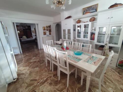 a dining room with a white table and chairs at Vaso' s Home in Koropíon