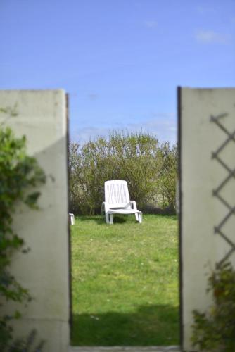 une chaise blanche assise dans l'herbe dans un miroir dans l'établissement Le Cottage de la Baie - vue mer en Baie de Somme, à Woignarue
