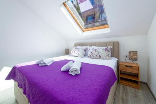 a bedroom with a purple bed with towels on it at Peaceful apartment near the beach - Sole in Zaton