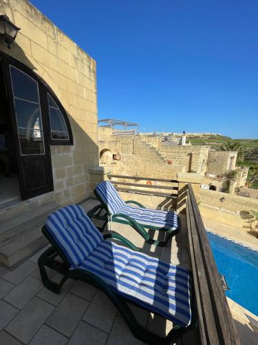 two blue and white chairs on a balcony with a pool at Soluna Boutique Guesthouse in Għasri