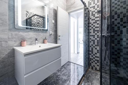 La salle de bains est pourvue d'un lavabo blanc et d'une douche. dans l'établissement Peaceful apartment near the beach - Sole, à Zaton