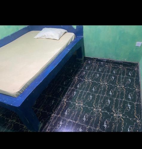 1 cama con marco azul y suelo negro en Karemi’s Lounge Bar & Guesthouse., en Malindi