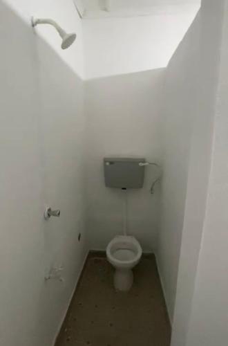 a bathroom with a toilet in a white room at Karemi’s Lounge Bar & Guesthouse. in Malindi