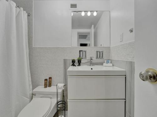 Baño blanco con lavabo y aseo en Cozy Beachfront Condo w Beach Service 1410, en Miami Beach