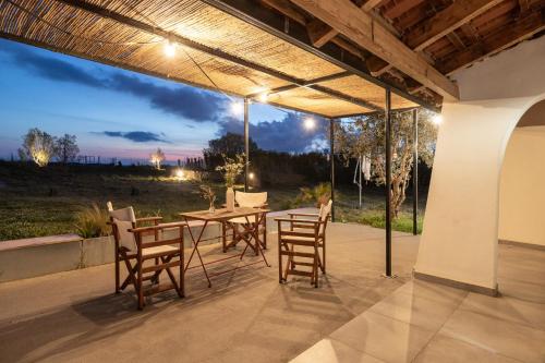 um pátio com uma mesa e cadeiras sob um telhado em House on the Sand close to Olympia em Katakolo