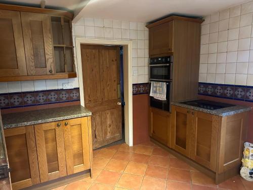 a kitchen with wooden cabinets and an open door at Trowbridge Lodge in Trowbridge