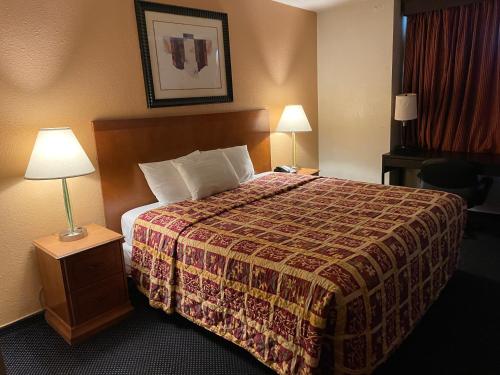 um quarto de hotel com uma cama e duas lâmpadas em Grand Inn em Fullerton