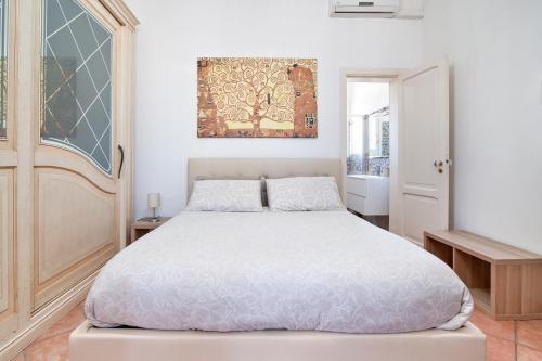 een slaapkamer met een wit bed en een schilderij aan de muur bij The golden hour, luxury apartment with a panoramic view in Lecce