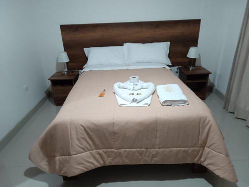 Una cama con dos toallas y una bata. en HOSPEDAJE EL EMPERADOR CAJAMARCA, en Cajamarca