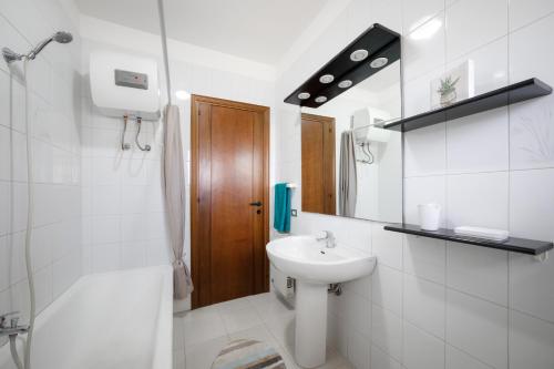 a white bathroom with a sink and a shower at Casa Acqua Marina vicino al mare con parcheggio privato in Quartu SantʼElena